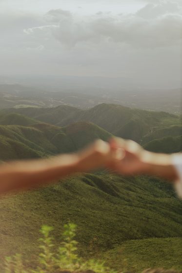Two hands reaching toward each other over mountains