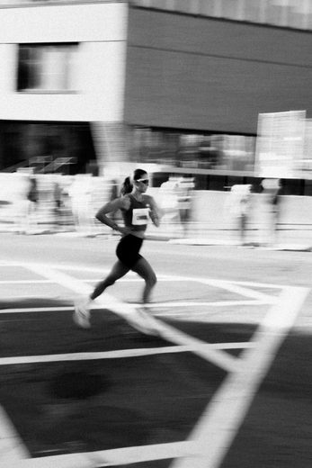 A runner mid-stride crossing a city street